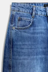 Jeans de tiro medio con cinco bolsillos, pernera holgada y diseño barrel, con costuras decorativas frontales y cierre de cremallera y botón.