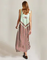 Vestido largo sin mangas con escote redondo, confeccionado en viscosa con un estampado geométrico tipo ikat en tonos marrones, naranjas y blancos, con detalle de texto en el ruedo.