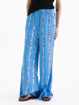 Pantalón de corte holgado y piernas rectas, confeccionado en popelina satinada de color celeste con estampado floral en franjas verticales. Cuenta con cintura elastizada y bolsillos delanteros.