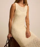 Vestido midi color crema, tejido en punto texturizado, sin mangas y con cuello redondo.