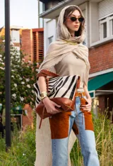 Cartera Taba Handbag de cuero y pelo con estampado animal print de cebra, combinada con detalles en cuero marrón y costuras decorativas visibles.