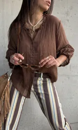 Camisa oversize color chocolate con cuello con volados, mangas abullonadas y cierre frontal con botones.