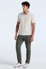 Polo de hombre color beige claro, de manga corta, con cuello y puños ribeteados en color marrón oscuro. Presenta un pequeño logo bordado en el pecho.