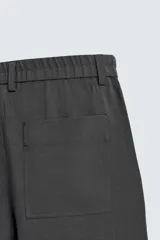 Pantalón de corte relaxed fit, con cintura ajustable, bolsillos delanteros y bolsillo trasero de plastrón. Presenta cierre frontal con cremallera y botón.