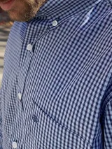 Camisa de corte clásico con estampado de cuadros en tonos rosados y celestes, con cuello abotonado, manga larga y bolsillo frontal con detalle bordado.