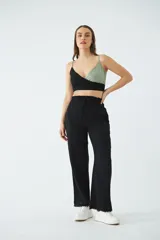 Blusa corta tipo top con diseño cruzado en escote en V, confeccionada en combinación de colores negro y verde. Presenta tirantes finos ajustables y detalle de grifa de cuero.