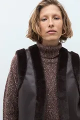 Chaleco reversible de corte recto, con un lado de cuero sintético color chocolate y el otro lado de piel sintética al tono. Presenta cuello redondo y diseño sin mangas.