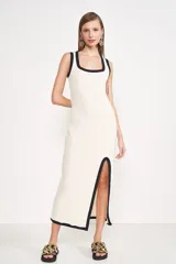 Vestido midi de punto color crema, con escote cuadrado, breteles anchos con ribete negro y abertura lateral en la falda con ribete negro.