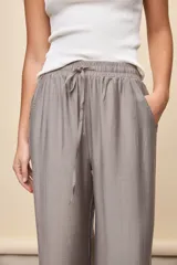 Pantalón gris de corte amplio y silueta fluida, con cintura elástica y cordón ajustable.