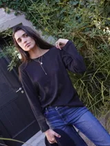 Remera de manga larga color negro, con cuello redondo y logo bordado sutilmente en el pecho.