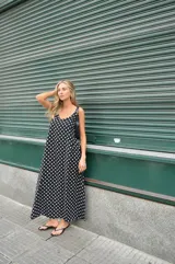 Vestido largo de crepe con estampado de lunares negros sobre fondo blanco. Presenta un diseño de corte holgado con breteles finos y escote redondeado.