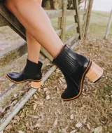 Botín de cuero vacuno negro con elásticos laterales, taco de madera con folia de cuero de 7cm y suela de 1cm. Horma de punta fina y caña de 12cm.