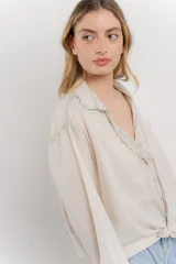 Camisa color crema de algodón con cuello camisero, botones y detalles de encaje en el escote.