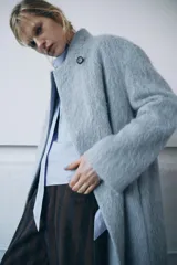 Abrigo recto de corte clásico confeccionado en una mezcla de lana Manteco y alpaca. Presenta cuello solapa, cierre frontal con un único botón visible y mangas largas. Diseño de textura suave y acabado elegante.