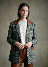 Blazer de paño de lana con diseño de pata de gallo en tonos gris y negro. Presenta cuello y detalles en los bolsillos de cuero color suela, con un corte relajado y cierre frontal de botones.