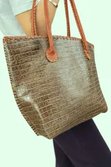 Cartera de mano tipo shopper, de cuero con textura crocco en tono marrón y tostado, con manijas largas y detalles de costuras artesanales.