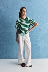 Remera de calce relajado con diseño a rayas horizontales blancas y verdes, hombros caídos y mangas amplias con vuelta. Presenta cuello redondo y ruedo trasero levemente más largo.