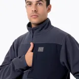 Buzo polar de microfleece con media cremallera, cuello alto y bolsillo frontal con cierre. Presenta paneles de contraste en nylon ripstop en la zona del pecho y detalles elásticos en puños y ruedo.