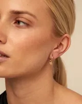 Dije de piercing dorado con forma de trébol de cuatro hojas.