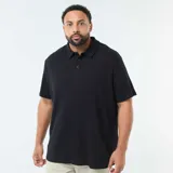 Polo negro de manga corta con cuello y tapeta de tres botones. El tejido presenta una textura de punto waffle o piqué sutil.