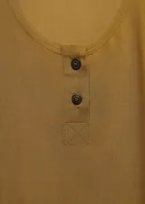 Musculosa de tejido fluido color verde oliva, con escote redondo, tirantes anchos y detalle de botones decorativos en el frente.