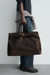 Bolso de mano de piel marrón oscuro de alta calidad con detalle de cinturón decorativo con hebilla metálica dorada y dos asas cortas.