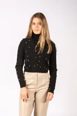 Sweater negro de cuello alto, con diseño de tejido trenzado y apliques de tachas metálicas circulares distribuidas por toda la prenda. Posee mangas largas con puños acanalados.