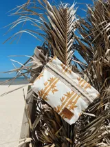 Sobre de tela color crudo con estampado de cañas color mostaza, detalles en yute y pulsera personalizada.