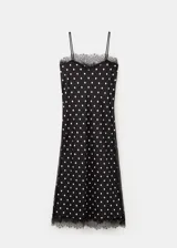 Top largo de tejido satinado color negro con estampado de lunares blancos, diseño recto, tirantes finos y ribetes de encaje negro en el escote y el ruedo.