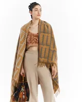 Manta de tejido grueso con flecos en los bordes, color mostaza y gris, con diseño de monograma repetitivo.