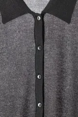 Polo de punto con hilo metalizado, de color gris oscuro, cuello solapa, manga larga con puños ajustados y cierre frontal de botones.