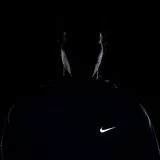 Campera deportiva Nike Miler negra con cierre frontal, capucha y logo Swoosh blanco en el pecho. Presenta un diseño con paneles en zigzag en la parte delantera y un detalle reflectante en la manga.