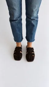 Sandalias planas de cuero marrón oscuro, con diseño de tiras entrelazadas y puntera cuadrada.