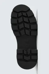 Bota tipo Chelsea de caña media, confeccionada en material sintético liso color negro. Presenta paneles elásticos laterales, tirador trasero y suela track con volumen.