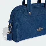 Minibolsa tipo bowling de Adidas Originals confeccionada en denim azul, con asas superiores, correa de hombro desmontable, cierre de cremallera y detalle del logo Trefoil metálico en el frente.
