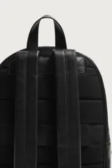 Mochila de cuero negro con compartimento principal y bolsillo frontal, ambos con cierre de cremallera. Incluye asa de mano superior, correas de hombro ajustables y parte posterior acolchada con banda de sujeción para equipaje.