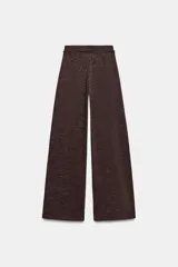 Pantalón de tiro alto y pierna recta, confeccionado en tejido piqué color beige. Presenta cintura elástica y un cinturón fino a contraste en color negro con detalle de pieza metálica central.