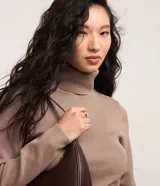 Suéter de punto color borgoña, con cuello alto estructurado y mangas largas.