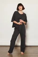 Pantalón de corte relajado color negro con efecto lavado, confeccionado en mezcla de algodón orgánico. Presenta una cintura elástica para mayor comodidad y bolsillos superpuestos a la altura de las rodillas, fusionando un estilo utilitario con el confort de una prenda de ocio.