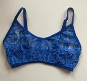 Conjunto de lencería compuesto por un top bralette de encaje azul con breteles ajustables y bombacha tipo less de encaje regulable en los laterales.