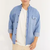 Camisa celeste de jean con cuello mao, manga larga con puños abotonados y bolsillo en el pecho.