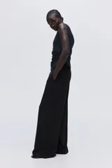 Pantalón de tiro alto con piernas amplias, cierre frontal con botón oculto y corchetes. Presenta bolsillos al bies en los laterales, bolsillos insertados en la parte trasera y pliegues marcados tanto en el frente como en la parte posterior.