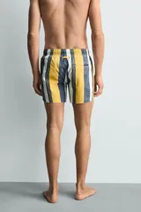 Bañador de hombre con estampado de rayas verticales anchas en tonos amarillo mostaza, azul oscuro desgastado, blanco y gris. Posee cintura elástica con cordón ajustable y bolsillos laterales.