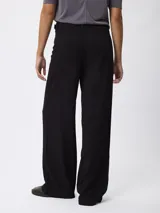 Pantalón de corte recto y pierna ancha, color beige, con cintura de tiro medio y cierre frontal.