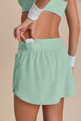 Pollera deportiva color rosa fucsia, con estampado en relieve de texto. Es de corte corto con ruedo redondeado y cuenta con shorts internos.