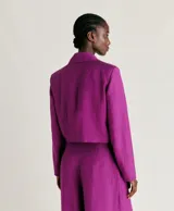 Blazer corto color fucsia de lino y viscosa, con solapas de muesca, cierre cruzado con dos botones, bolsillo en el pecho y forro completo.