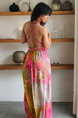 Vestido largo de seda con estampado abstracto en tonos marrones, beige y destellos dorados, con escote en V profundo, tirantes de cuerda anudados al cuello y la cintura, y tajo lateral en la falda.