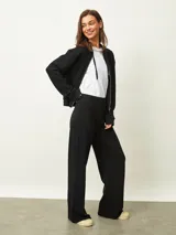 Campera negra con capucha, cierre frontal, mangas largas con puños elásticos y bolsillos laterales.