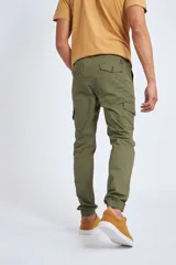 Pantalón cargo color beige con ajuste slim, cierre frontal con botón, bolsillos laterales tipo cargo y puños elásticos en los tobillos.