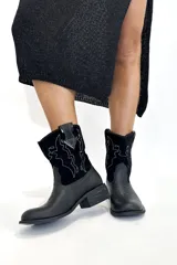 Bota tejana de cuero negro con bordado de cactus en hilo blanco.